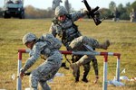 Soldiers leap over a barricade during the fallen comrade event at the Winston P. Wilson shooting matches held at Camp Joseph T. Robinson in North Little Rock, Ark., Oct. 24-29, 2010. The event had Soldiers run a total of 200 yards, while negotiating obstacles and carrying a dummy. In the middle of the event, they lie prone and knock down seven targets with rifle fire.
