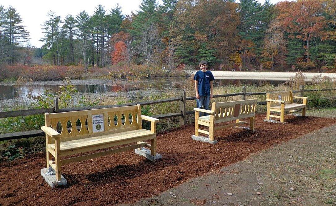 Boy Scout Jacob Piotrowski stands near his completed military memorial bench project at West Hill Dam, Uxbridge, Massachusetts. 