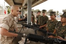 Sgt. Christopher R. Garcia, embarkation specialist, logistics section, 15th Marine Expeditionary Unit, explains weapons capabilities to a group of cadets with El Camino High School's Junior Reserve Officer Training Corps at the MEU's armory in Camp Del Mar.  Aug. 16.  Marines and sailors of the MEU educated a portion of the school's JROTC where they spent two days on base living like Marines to better their understanding of the operational side of the Marine Corps.  Garcia, 24, is native of Denver.  