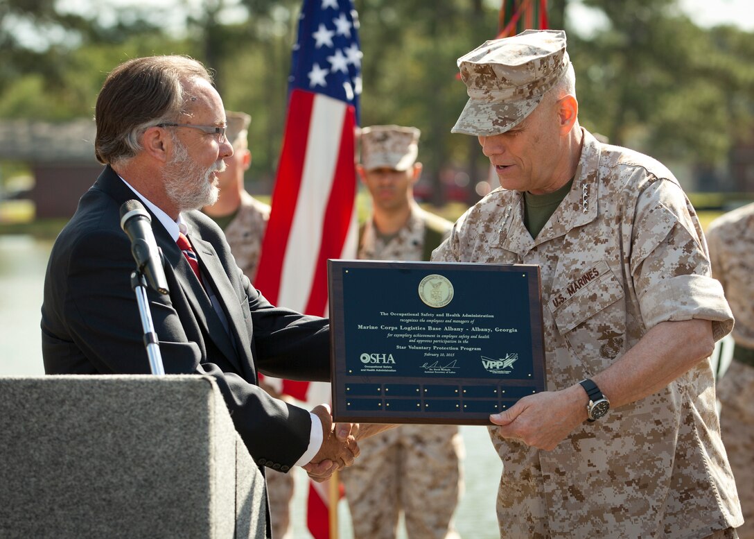 The Area Director of Occupational Safety and Health Administration (OSHA), Robert E. Vazzi, left, presents the Voluntary Protection Programs (VPP) Star Site award to the Assistant Commandant of the U.S. Marine Corps, Gen. John M. Paxton, Jr., and the Commanding Officer of Marine Corps Logistics Base Albany, Col. Donald J. Davis, not shown, during the VPP Star Site Ceremony at Marine Corps Logistics Base Albany, Ga., May 5, 2015. Marine Corps Logistics Base Albany earned the highest honor VPP Star from OSHA by being committed to safety excellence far beyond OSHA requirements. (U.S. Marine Corps photo by Cpl. Tia Dufour/Released)
