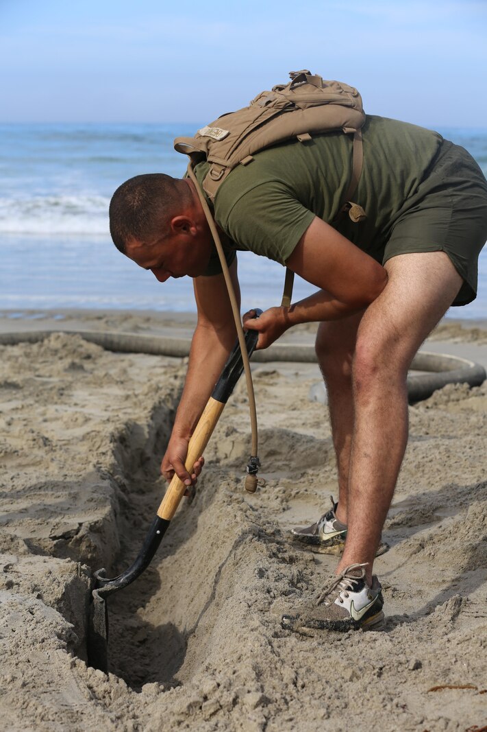 U.S. Marine Corps Cpl. Nelson Bernal, bulk fuel specialist with Bulk Fuel Company, 7th Engineer Support Battalion, 1st Marine Logistics Group, digs a trench to hold a portion of a suction hose on Camp Pendleton Calif., May 1, 2015. The suction hose is used as part of the Beach Unloading System used to house fuel, which is pumped from a ship off shore. (U.S. Marine Corps Photo by Cpl. Rodion Zabolotniy, Combat Camera/Released)