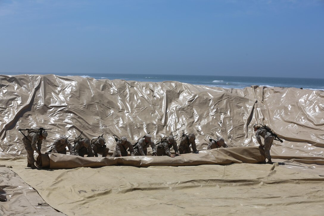 U.S. Marines with Bulk Fuel Company, 7th Engineer Support Battalion, 1st Marine Logistics Group, roll out a 50,000 gallon bag on Camp Pendleton, Calif., May 1, 2015. The 50,000 gallon bag is used as part of the Beach Unloading System used to house fuel, which is pumped from a ship off shore. (U.S. Marine Corps Photo by Cpl. Rodion Zabolotniy, Combat Camera/Released)