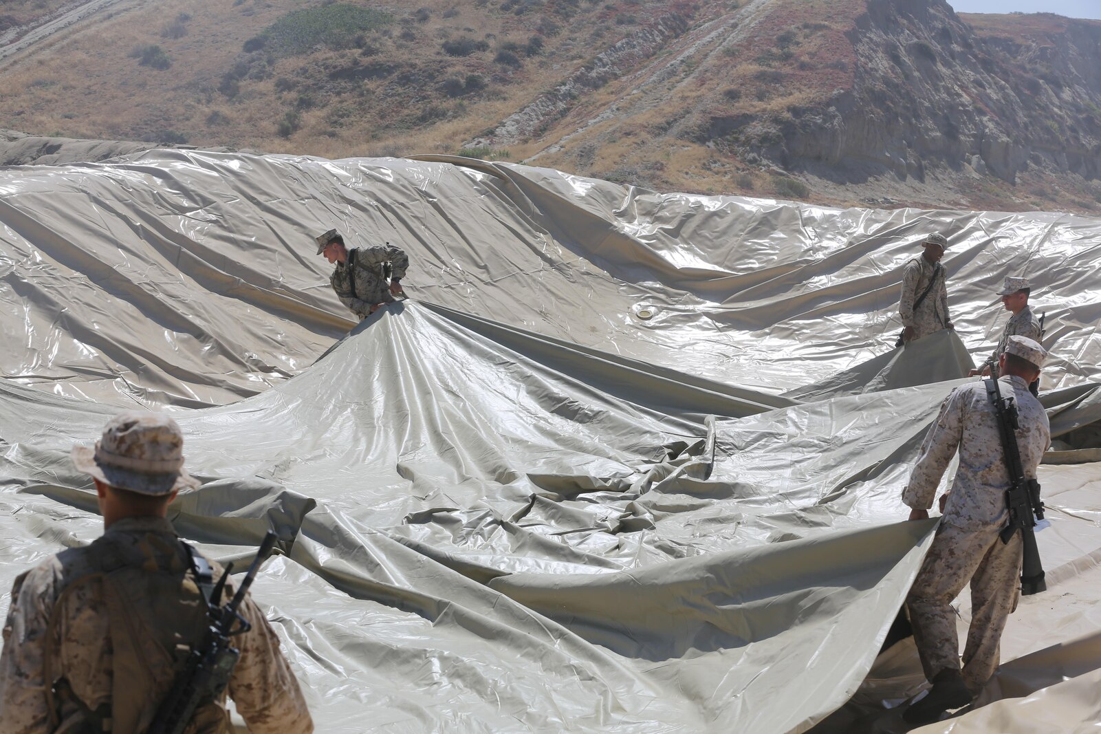 U.S. Marines with Bulk Fuel Company, 7th Engineer Support Battalion, 1st Marine Logistics Group, roll out a bag liner on Camp Pendleton, Calif., May 1, 2015. The bag liner is used as part of the Beach Unloading System used to house fuel which is pumped from a ship off shore. (U.S. Marine Corps Photo by Cpl. Rodion Zabolotniy, Combat Camera/Released)