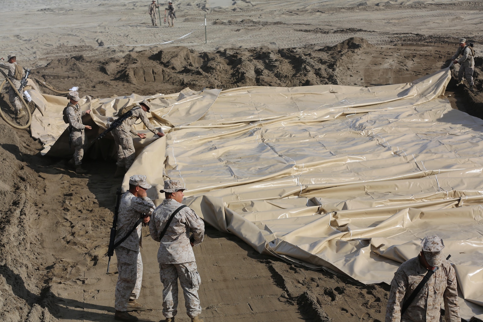 U.S. Marines with Bulk Fuel Company, 7th Engineer Support Battalion, 1st Marine Logistics Group, roll out a berm liner on Camp Pendleton Calif., May 1, 2015. The berm liner is used as part of the Beach Unloading System used to house fuel, which is pumped from a ship off shore. (U.S. Marine Corps Photo by Cpl. Rodion Zabolotniy, Combat Camera/Released)