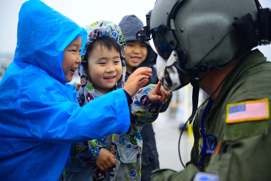 Local children admire the face-shield of Staff Sgt. Christopher Rector, 459th Airlift Squadron flight engineer during Friendship Day 2015 at Marine Corps Air Station Iwakuni, Japan, May 3, 2015. The event allowed visitors the opportunity to interact with Japanese and American service members. (U.S. Air Force photo by Tech. Sgt. Melissa K. Mekpongsatorn/Released)