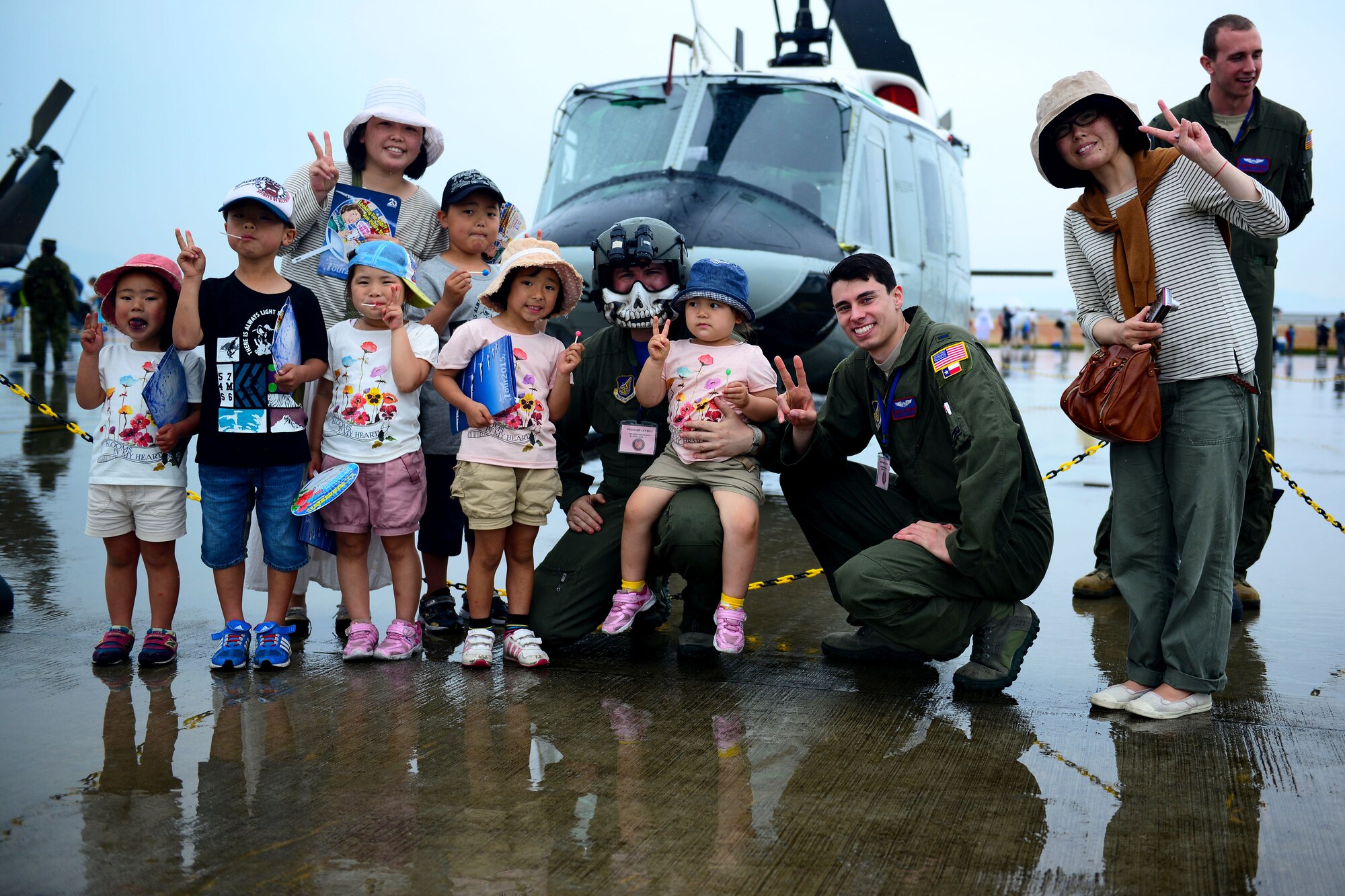 A group poses for a photo with 1st Lt. Daniel Trapani, 459th Airlift Squadron UH-1N pilot, and Staff Sgt. Christopher Rector, 459th AS flight engineer, both from Yokota Air Base, Japan, during the first-ever joint Friendship Day 2015 Air Show hosted by Marine Corps Air Station Iwakuni, Japan, and Japan Maritime Self-Defense Force at MCAS Iwakuni, Japan, May 3, 2015. The event allowed visitors the chance to see several aircraft demonstrations and gave them the opportunity to interact with Japanese and American service members. (U.S. Air Force photo by Tech Sgt. Melissa K. Mekpongsatorn/Released)