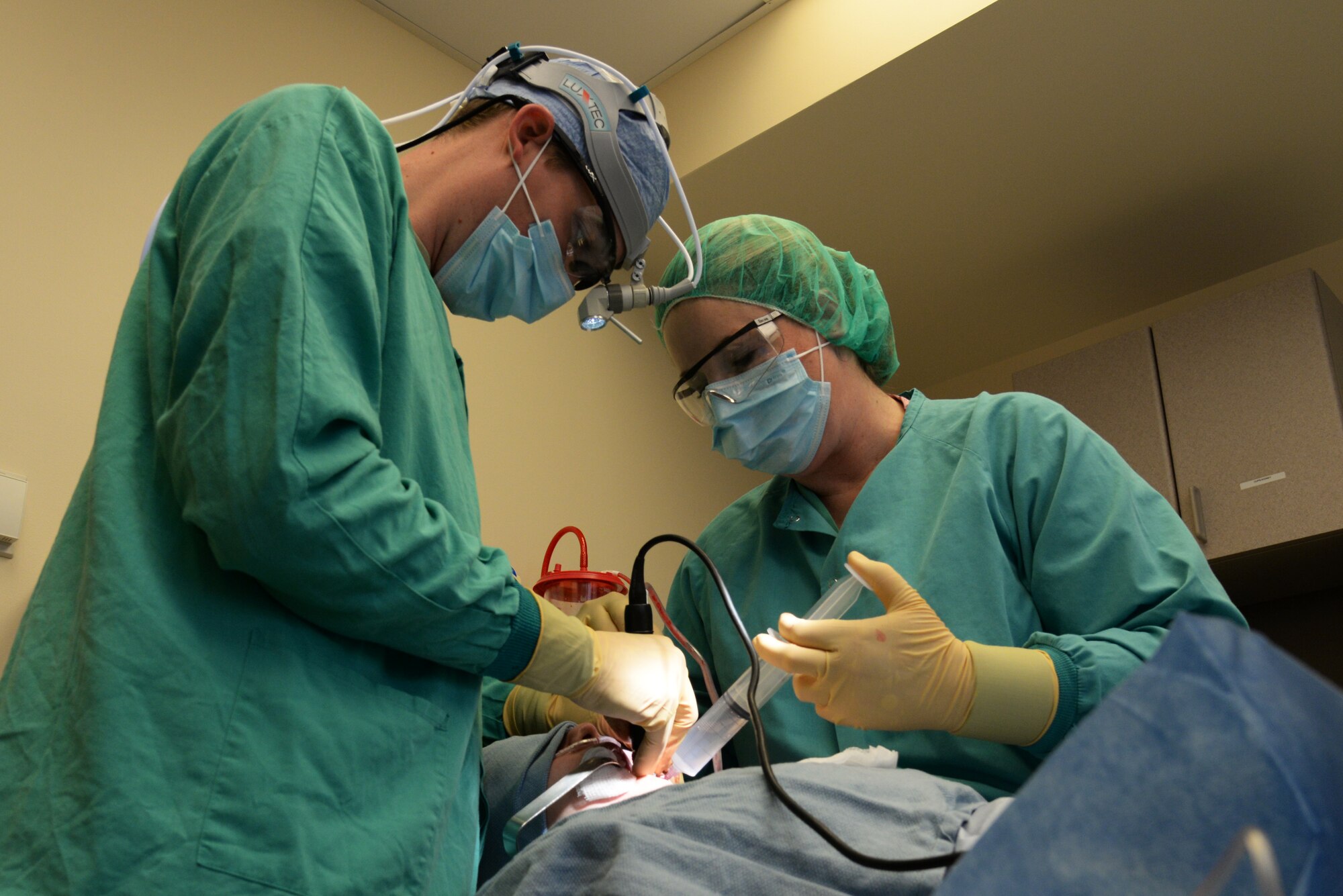 Capt. Kyle Christensen and Lisa Whisenhunt perform a wisdom teeth extraction April 8, 2015, at the Scott Clinic, Scott Air Force Base, Illinois. Wisdom teeth are extracted to correct or prevent future problems that may occur. Christensen is a General Dentist and Whisenhunt is a Dental Technician from the 375th Dental Squadron. (U.S. Air Force Photo by Airman 1st Class Megan Friedl)