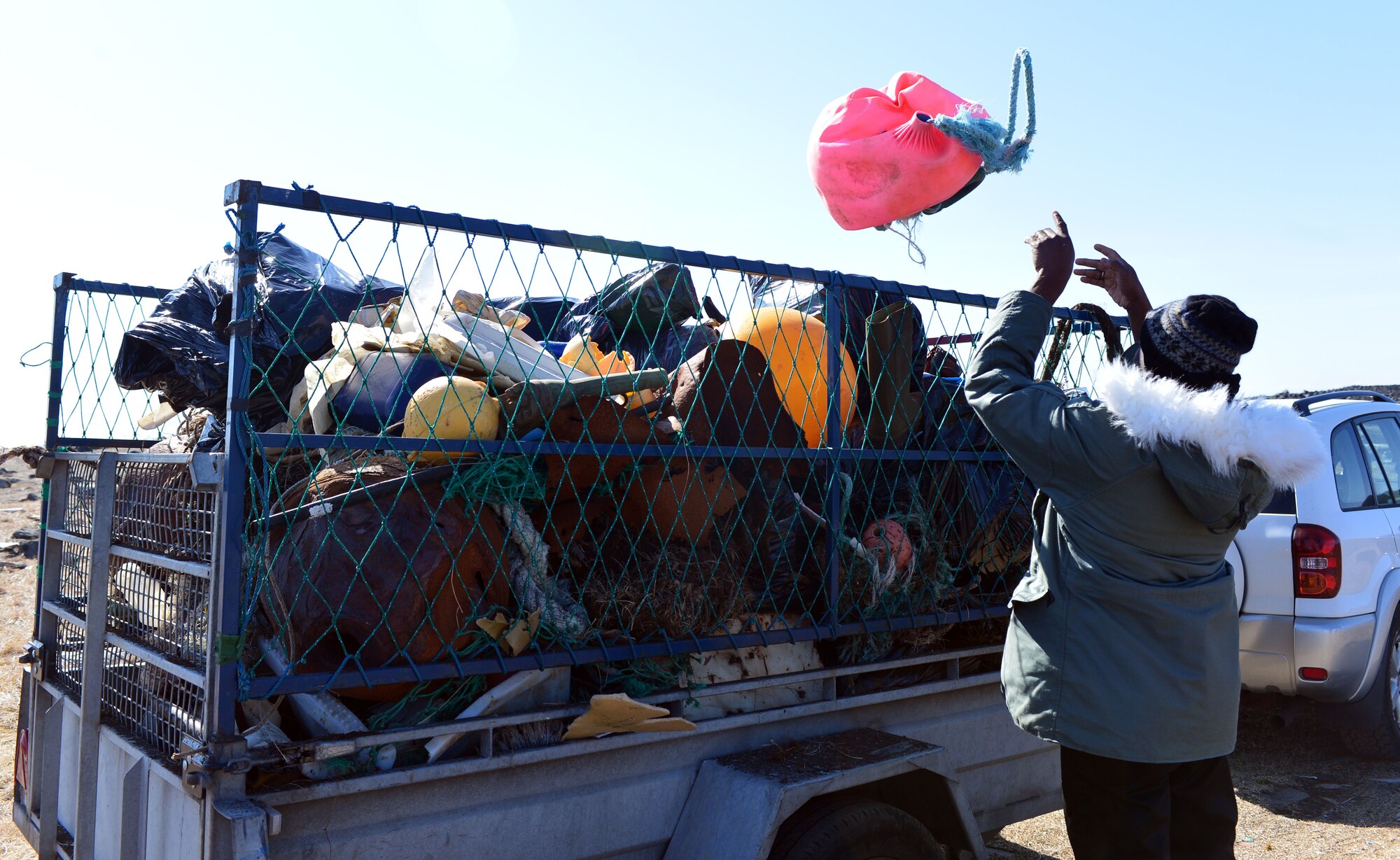 U.S. Air Force Chaplain (Capt.) Sean Ballard of the 871st Air Expeditionary Squadron tosses debris into a trailer during a beach clean-up on the Reykjanes Peninsula, Iceland, May 2, 2015. Airmen who deployed to Iceland for Icelandic Air Surveillance and Policing and members of the Blue Army, an Icelandic environmental organization, filled two trailers with trash and debris found during the service event. (U.S. Air Force photo by 2nd Lt Meredith Mulvihill/Released)