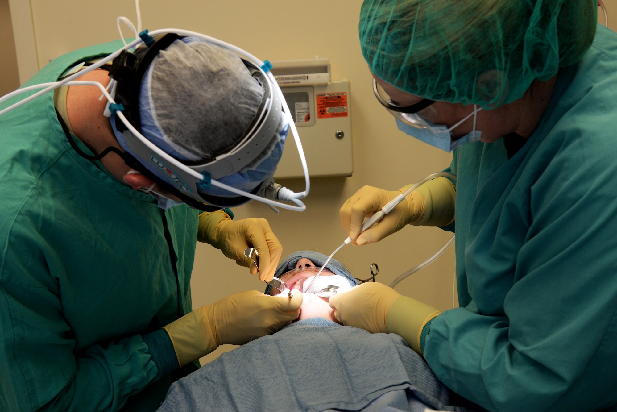 Capt. Kyle Christensen and Lisa Whisenhunt perform a wisdom teeth extraction April 8, 2015, at the Scott Clinic, Scott Air Force Base, Illinois. Wisdom teeth are extracted to correct or prevent future problems that may occur. Christensen is a General Dentist and Whisenhunt is a Dental Technician from the 375th Dental Squadron. (U.S. Air Force Photo by Airman 1st Class Megan Friedl)