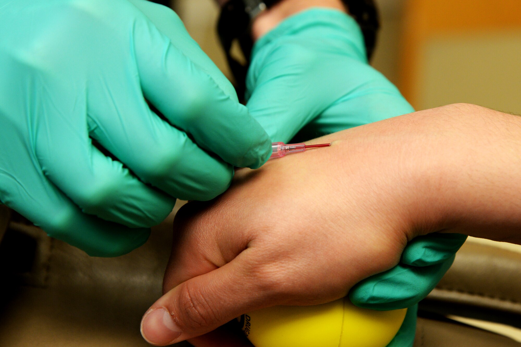 Capt. Kyle Christensen, 375th Dental Squadron General Dentist, positions a needle into a patient's hand to deliver saline April 8, 2015, at the Scott Clinic, Scott Air Force Base, Illinois. The patient received saline during a wisdom teeth extraction. (U.S. Air Force Photo by Airman 1st Class Megan Friedl) 