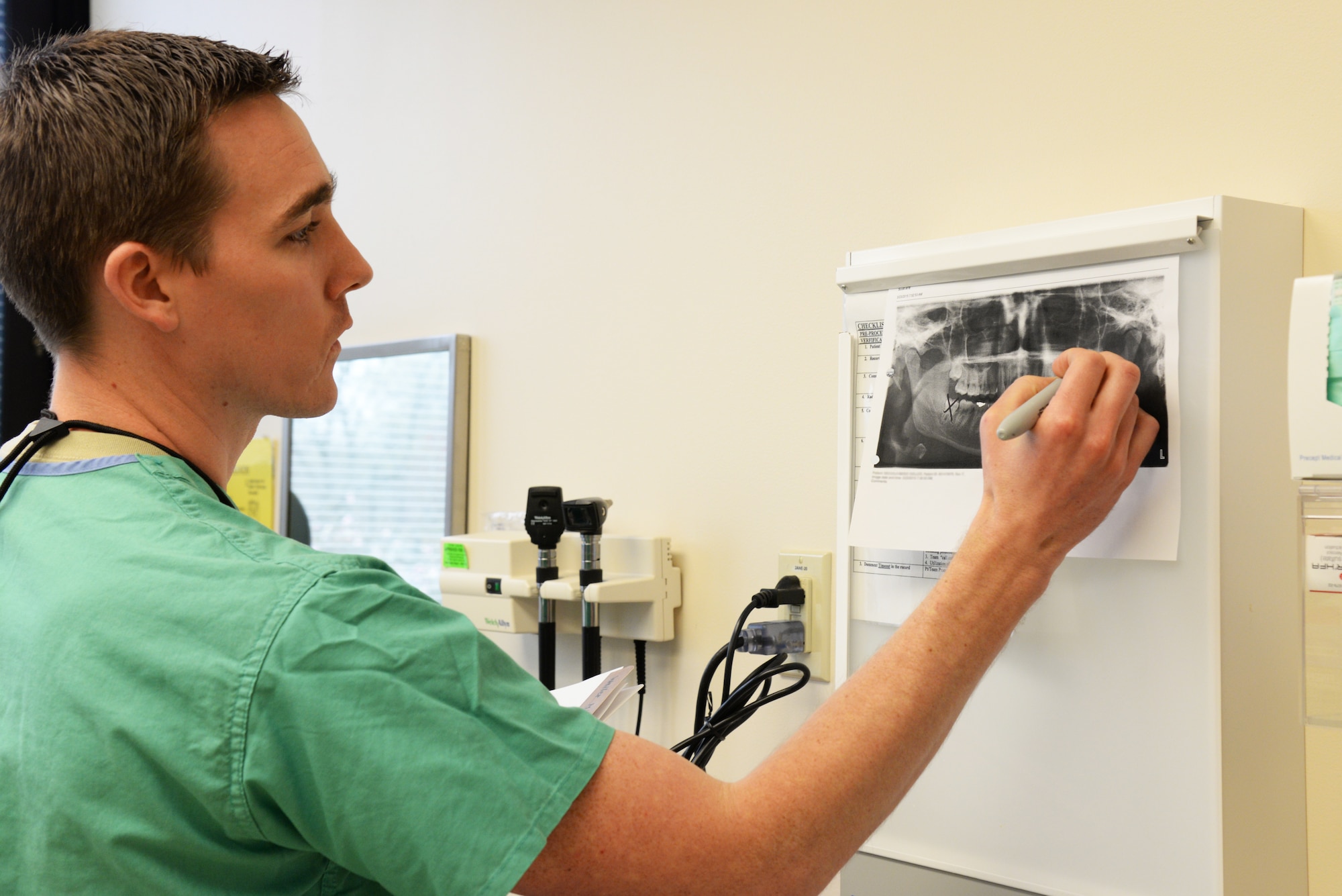 Capt. Kyle Christensen, 375th Dental Squadron General Dentist, pinpoints the wisdom teeth that will be extracted on an x-ray of a patient's mouth April 8, 2015, at the Scott Clinic, Scott Air Force Base, Illinois. Wisdom teeth are extracted to correct or prevent future problems that may occur. (U.S. Air Force Photo by Airman 1st Class Megan Friedl) 