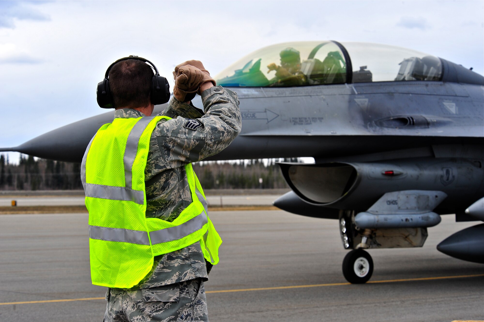 U.S. Air Force Staff Sgt. Matthew Clairday, an avionics technician with the 180th Fighter Wing, Toledo Air National Guard Base, Ohio, marshals an F-16 Fighting Falcon assigned to the 13th Fighter Squadron, Misawa Air Base, Japan, May 5, 2015, during RED FLAG-Alaska (RF-A) 15-2 at Eielson Air Force Base, Alaska.  The work completed by maintenance personnel provide mission-capable aircraft for pilots so they can provide air support, serving a vital role in the overall RF-A mission. (U.S. Air Force photo by Tech. Sgt. Miguel Lara III/Released)