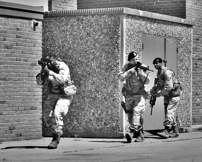 U.S. Air Force Senior Airmen Quatari Moodie and Kip Vaughan, 633rd Security Forces Squadron response force leaders, and Staff Sgt. Ervin Faison III, 633rd SFS base defense operations controller, approach a building during an exercise at Langley Air Force Base, Va., May 5, 2015. The exercise demonstrated what potential advantages increased patrol manning would provide in an emergency situation, such as an active shooter on base. (U.S. Air Force photo illustration by Airman 1st Class Devin S. Michaels/Released)