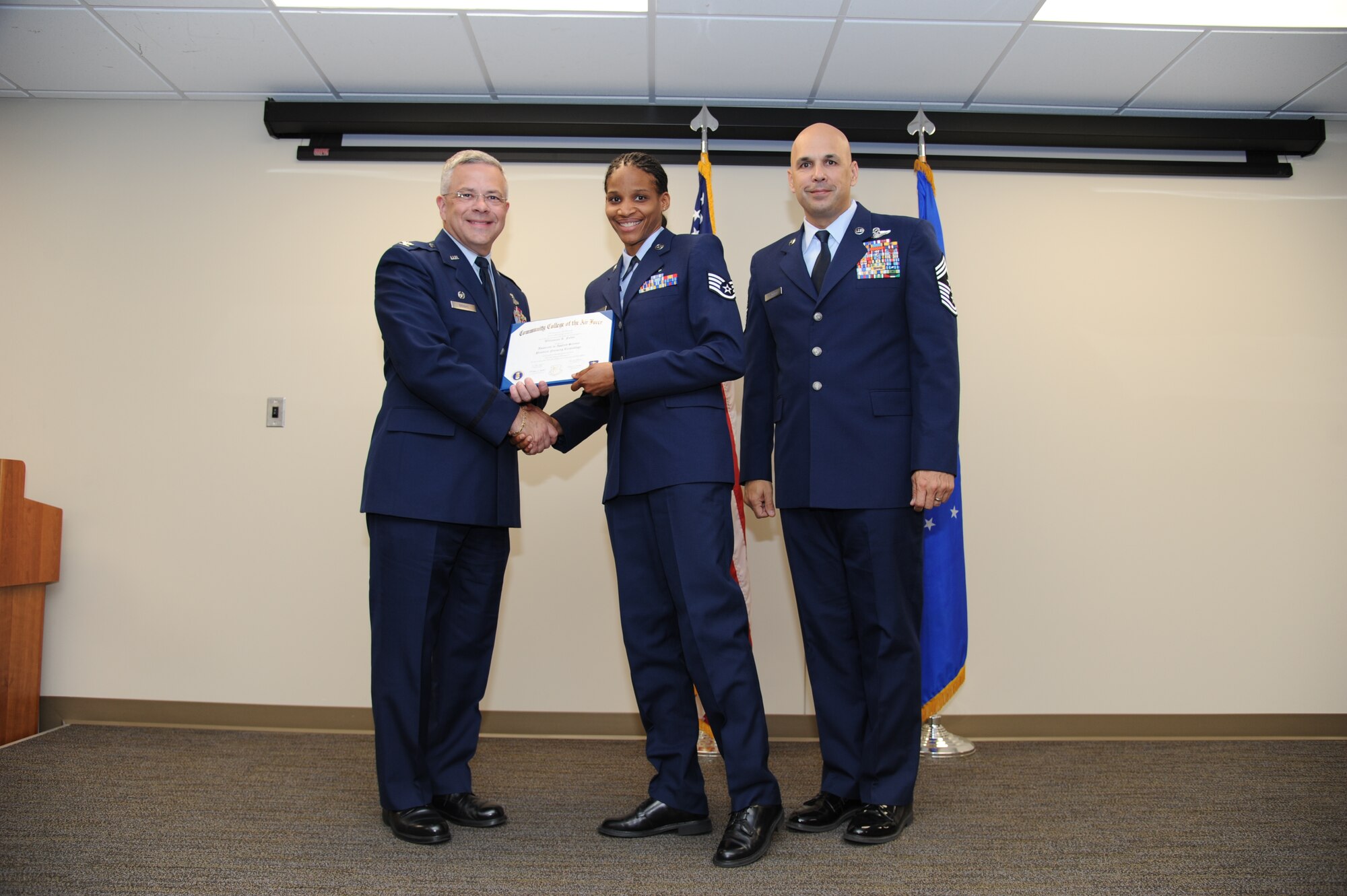 Col. Randal Bright, commander of the 927th Air Refueling Wing, MacDill Air Force Base, Fla., and Chief Master Sgt. Michael Klausutis, 927 ARW command chief present Staff Sgt. Willamina A. Folks her Community College of the Air Force diploma during a ceremony held here May 3, 2015. (U.S. Air Force photo/Tech. Sgt. Peter Dean)