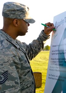 U.S. Air Force Tech. Sgt. Tyson Peek, 372nd Training Squadron F-22 Raptor egress instructor, signs his name on a display during the 4th Annual Standing Together Against Rape Road Rally at Langley Air Force Base, Va., April 29, 2015. Prior to the motorcycle run, riders, victim advocates and participants took turns sign a pledge to stop sexual assault. (U.S. Air Force photo by Senior Airman Breonna Veal/Released) 