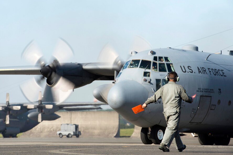 A crew chief with the 374th Aircraft Maintenance Squadron, guides a C-130 Hercules to the taxiway at Yokota Air Base, Japan, May 5, 2015. Members of Yokota left to provide humanitarian airlift and relief operations to support the U.S. Agency of International Development and the Government of Nepal in response to the 7.8 magnitude earthquake that devastated the country April 25, 2015. (U.S. Air Force photo by Staff Sgt. Cody H. Ramirez/Released)