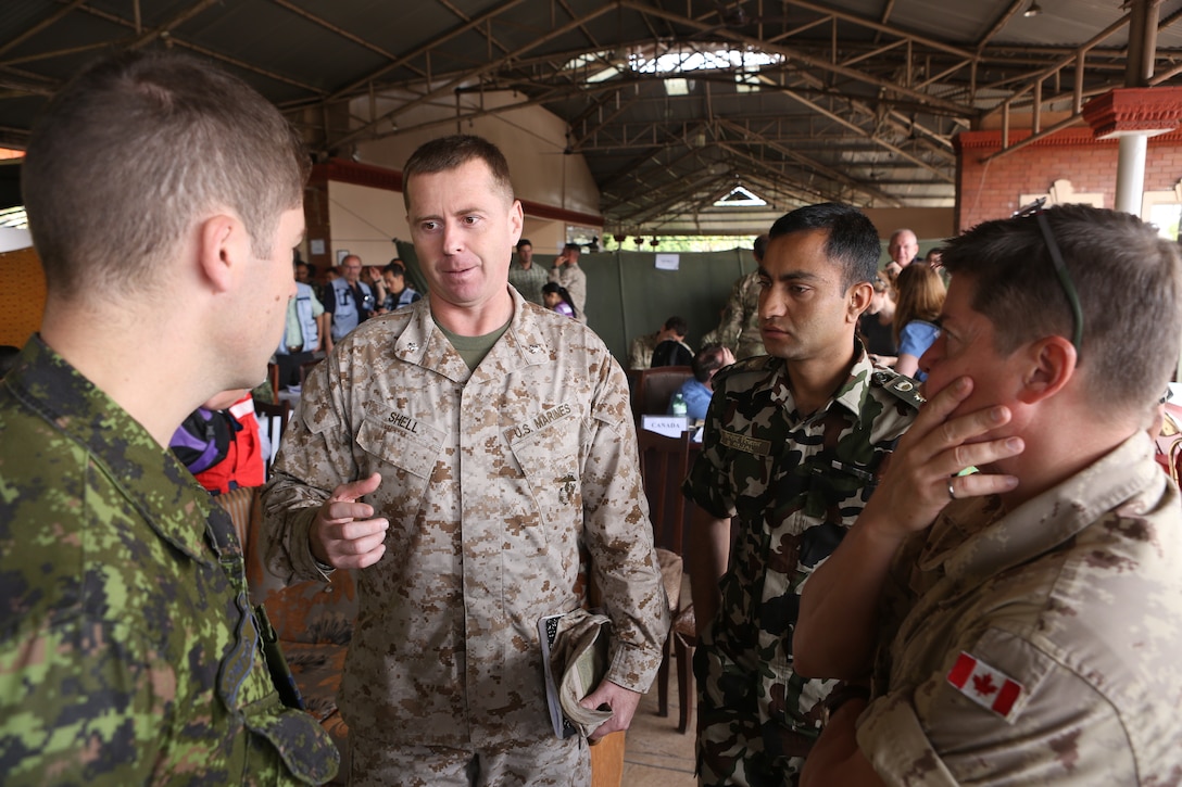 Marine Lt. Col. Jude Shell, second from left, of the 3rd Marine Expeditionary Brigade, talks with Nepalese and Canadian service members after the Multi-National Military Coordination Center's morning briefing in Kathmandu, Nepal, May 5, 2015. 