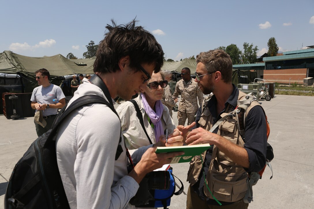 Ross Adkin of Reuters news agency, left, and Julie McCarthy of National Public Radio talk with Scott Aronson of USAID on May 5, 2015, in Nepal. 
