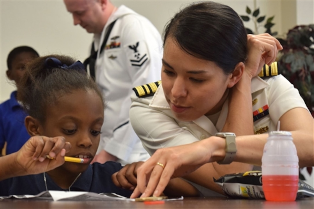 U.S. Navy Lt. Cmdr. Maura Thompson helps a child complete homework during Shreveport Navy Week in Shreveport, La., April 29, 2015. The child participates an after-school program through Volunteers of America. 