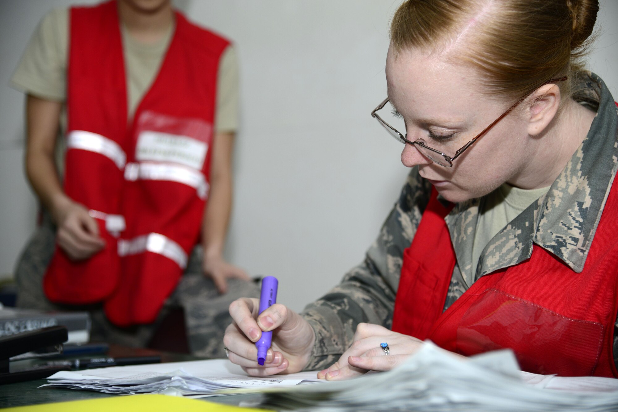 U.S. Air Force Staff Sgt. Kayla Eschler, a 386th Expeditionary Force Support Squadron Deliberate and Crisis Action Planning and Execution Segments technician, highlights paperwork while in-processing newcomers at an undisclosed location May 5, 2015. Personnel collected information such as copies of orders and emergency contact information from deployed members. (U.S Air Force photo by Senior Airman Racheal E. Watson/Released)