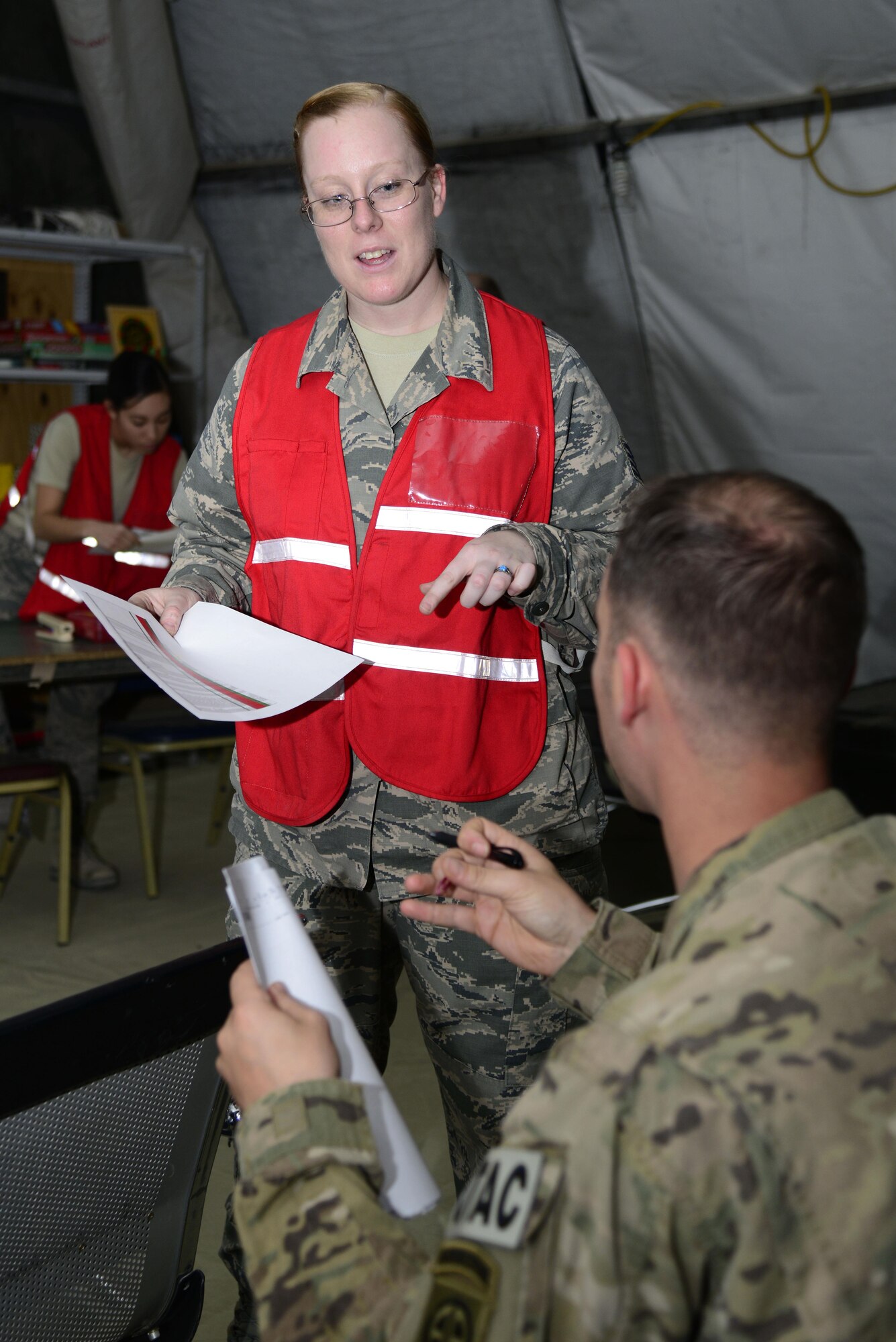U.S. Air Force Staff Sgt. Kayla Eschler, a 386th Expeditionary Force Support Squadron Deliberate and Crisis Action Planning and Execution Segments technician, answers questions from incoming personnel during in-processing at an undisclosed location May 5, 2015. Personnel Support for Contingency Operations briefed in-bound personnel and obtained paperwork for accountability purposes. (U.S Air Force photo by Senior Airman Racheal E. Watson/Released)