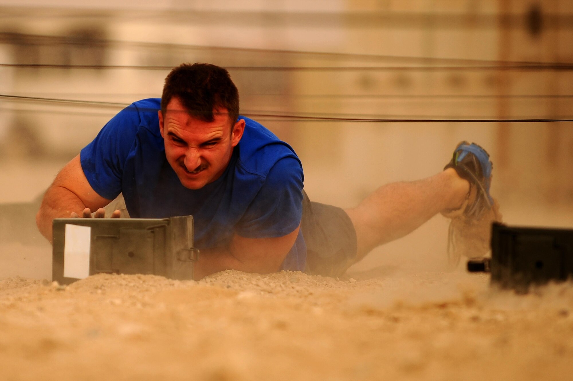 A U.S. Airmen assigned the 386th Air Expeditionary Wing supporting U.S. Central Command operations, participates in the low crawl portion of an Explosive Ordnance Disposal Memorial Challenge in Southwest Asia, May 2, 2015. The EOD Memorial Challenge consisted of a 1.5 mile run with obstacles such as tire flipping, pool plunging, low crawling, carrying sandbags. jumping over barriers and climbing walls.  (U.S. Air Force photo/Tech. Sgt. Brittany E. Jones/Released)