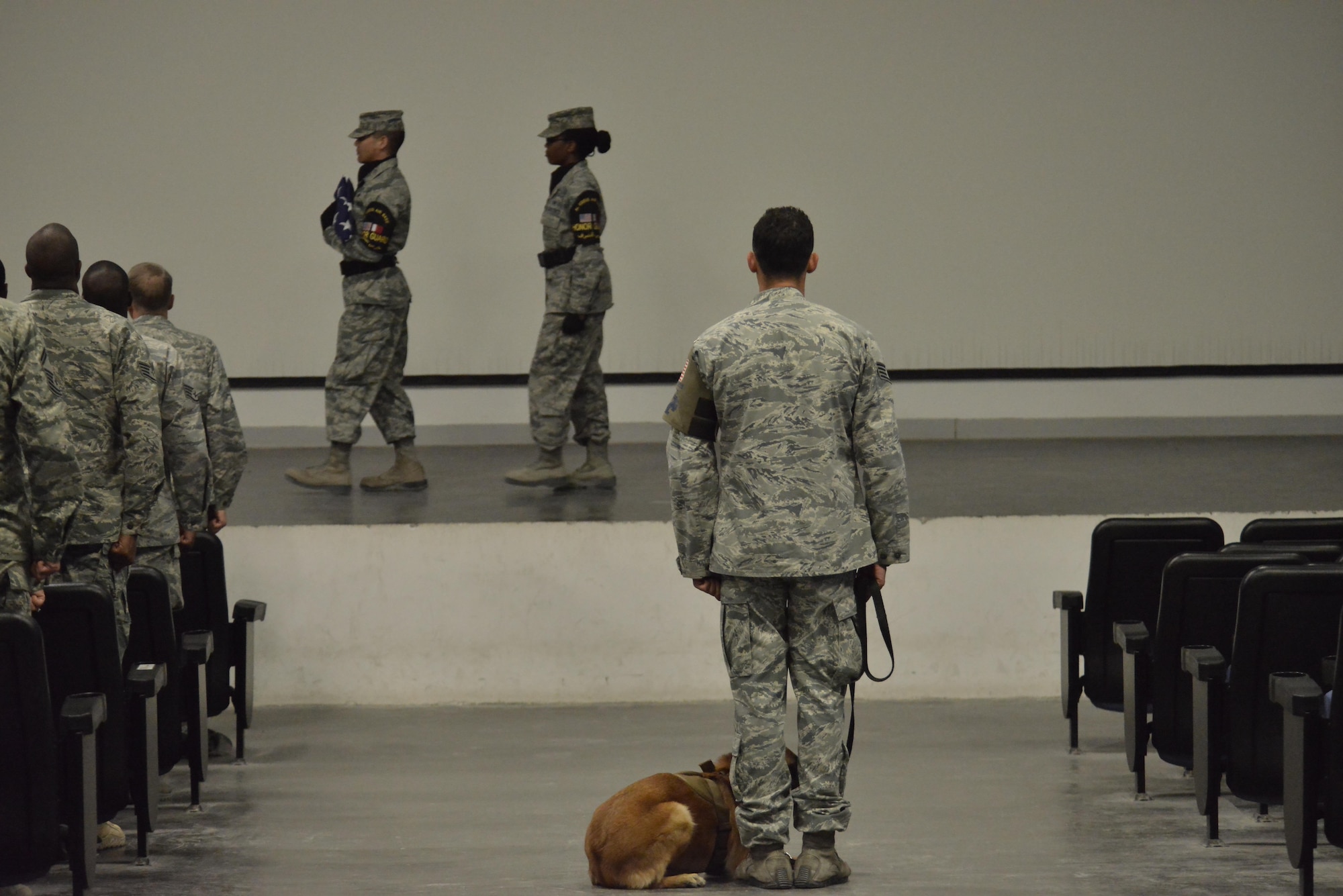 Ttilly, 379th Expeditionary Security Forces Squadron military working dog, sits next to her handler Staff Sgt. Jonathan Calo handler during the memorial service of MWD Jonny May 2, 2015 at the Blatchford-Preston Complex at Al Udeid Air Base, Qatar.  ( U.S. Air Force phot by Staff Sgt. Alexandre Montes)