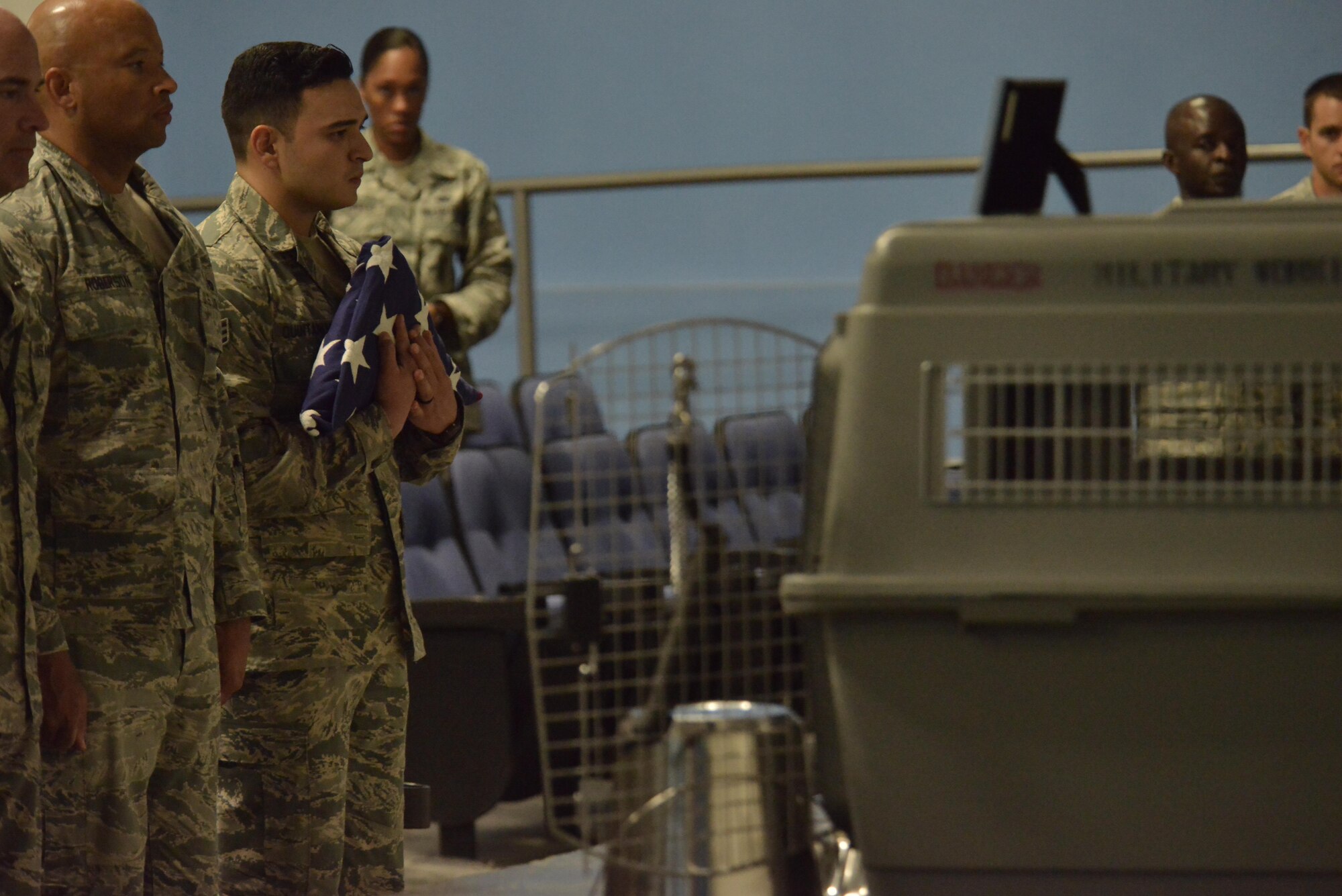 Senior Airman Jerry Quintanilla, 379th Expeditionary Security Forces Squadron holds a folded U.S. flag that was presented to him in honor of Military Working Dog Jonny May 2, 2015 at the Blatchford-Preston Complex at Al Udeid Air Base, Qatar.  Jonny and Quintanilla worked side by side daily for three months before Jonny passed away due to medical complications. ( U.S. Air Force photo by Staff Sgt. Alexandre Montes)