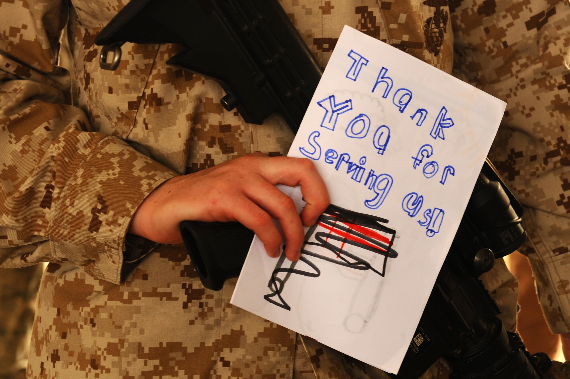 A U.S. Marine Corps member supporting the Special Purpose Marine Air Ground Task Force Crisis Response, Central Command, in Southwest Asia holds a piece of artwork , May 5, 2015. Rep. Susan Davis visited with female Service members shortly before Mother’s Day and gave them artwork created by children in California elementary schools. (U.S. Air Force photo/Tech. Sgt. Brittany E. Jones/Released)