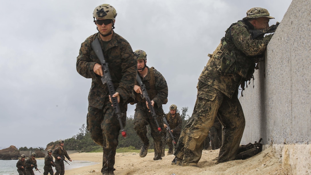 Japanese Ground Self-Defense Force soldiers post security as U.S. Marines advance on the beach during the Japanese Observer Exchange Program April 28, 2015 at Kin Blue. JOEP is a III Marine Expeditionary Force, 31st Marine Expeditionary Unit and JGSDF coordinated program designed to increase regional security, maintain unit readiness and enhance overall cooperation. This is the fourth iteration of JOEP for the 31st MEU after the initial partnership in September 2012. The Marines are with Battalion Landing Team 2nd Battalion, 4th Marines, 31st MEU. (U.S. Marine Corps photo by Cpl. Ryan C. Mains/Released)