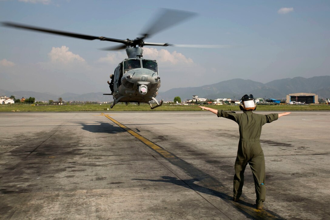 Cpl. Mackenzie Higgins guides a UH-1Y Huey for takeoff at the Tribhuvan International Airport in Kathmandu, Nepal, May 5. Marines with Marine Light Attack Helicopter Squadron 469 and Marine Medium Tilt Rotor Squadron 262 carried supplies in a UH-1Y Huey and MV-22 Ospreys to Charikot, Nepal. The supplies will provide Nepalese people with shelter after a 7.8 magnitude earthquake struck central Nepal, April 25, causing fatalities, injuries and significant damage. The government of Nepal declared a state of emergency and requested international assistance. The U.S. military, at the direction of the U.S. Agency for International Development, will continue to support Nepal as needed. HMLA-469 and VMM-262 are attached to Marine Aircraft Group 36, 1st Marine Aircraft Wing, III Marine Expeditionary Force. Higgins is a UH-1Y crew chief with HMLA-469 from Pala Way, California.