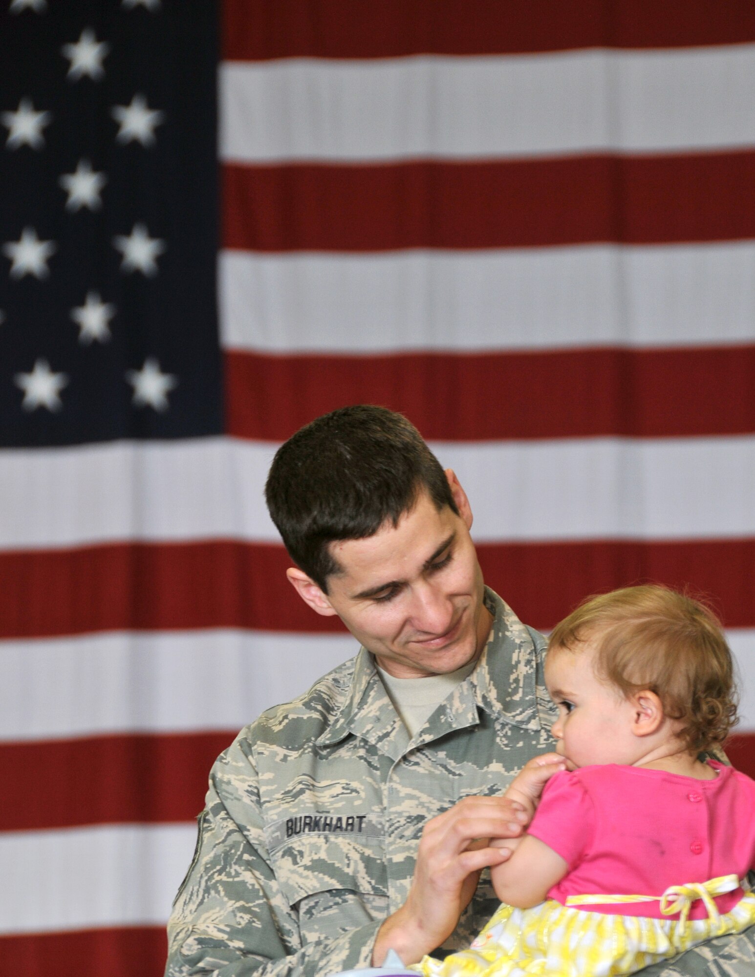 U.S. Air Force Tech. Sgt. Derrick Burkhart, 114th Maintenance Squadron munitions controller, holds his daughter Arianna, before the start of a mobilization ceremony at Joe Foss Field, S.D., May 3, 2015. Burkhart is part of the almost 250 members of the South Dakota Air National Guard’s 114th Fighter Wing preparing to depart for a four month deployment to South Korea where they will support the United States' continual commitment to stability and security in the region. (Photo by Tech. Sgt. Christopher Stewart)