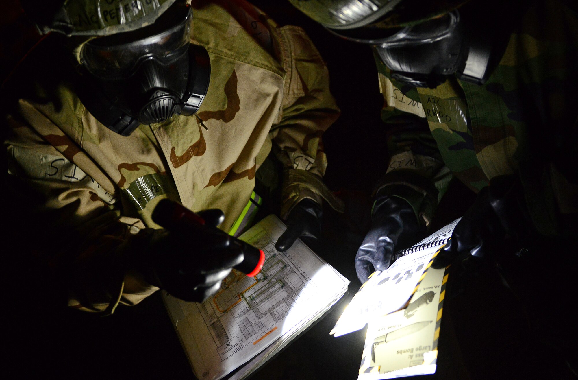 (From left) U.S. Air Force Airmen 1st Class Peter Gracey and Pablo Arroyo review the classification of a simulated unexploded ordinance during an inspection scenario, May 6, 2015, at Aviano Air Base, Italy. Inspection MAROON EXCAVATOR tested Airmen’s operational readiness. Gracey is a cyber transport systems technician and Pablo is a cyber surety technician from the 31st Communications Squadron. (U.S. Air Force photo by Senior Airman Matthew Lotz/Released)