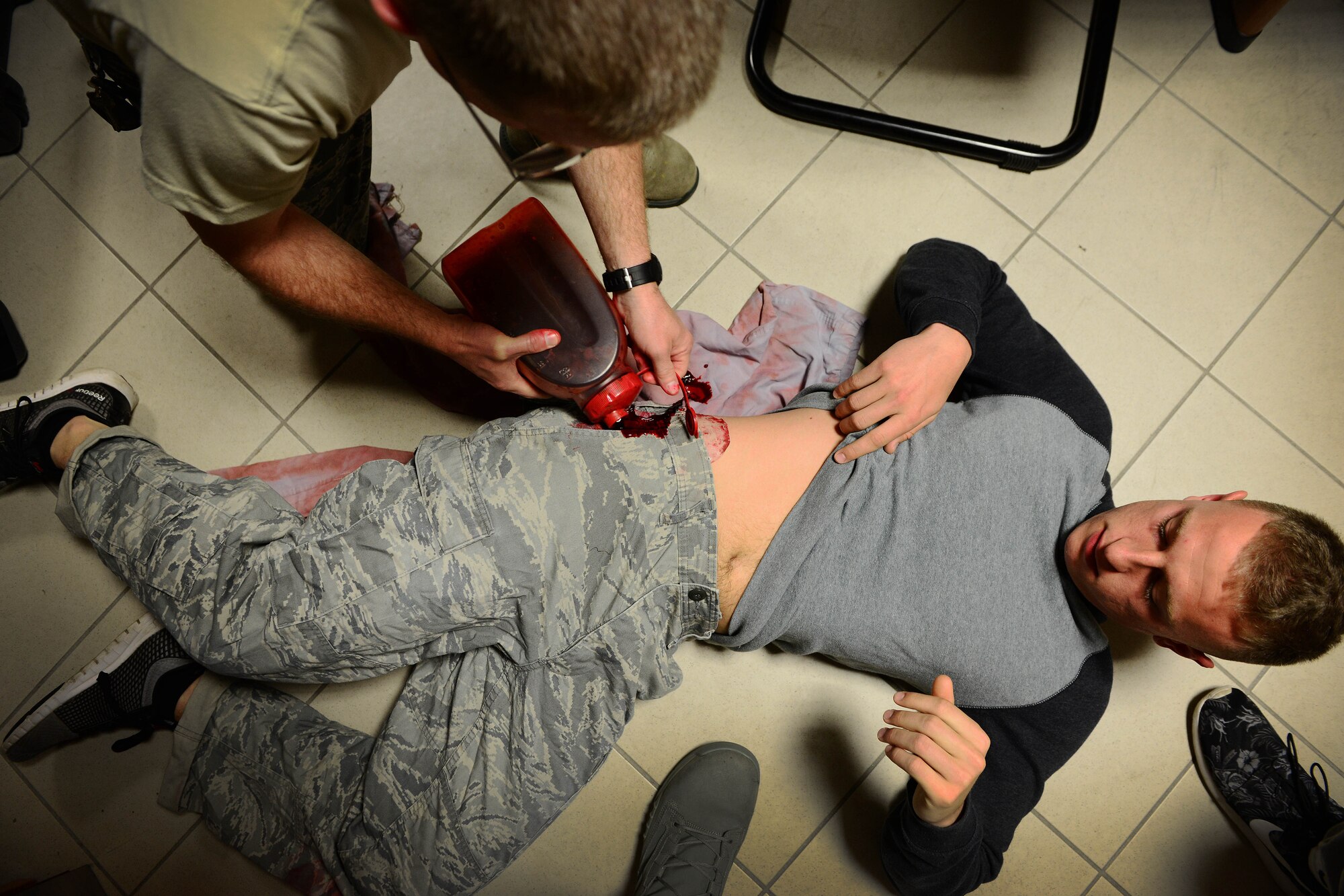 U.S. Air Force Lt. Col. Brian Hubbard, 31st Medical Operations Squadron medical services flight commander, pours fake blood on Airman 1st Class Blaytin Southerly, 31st Security Forces Squadron response force member, during inspection MAROON EXCAVATOR, May 5, 2015, at Aviano Air Base, Italy. The inspection allowed medical personnel to emulate real-world situations that participants may encounter. (U.S. Air Force photo by Senior Airman Matthew Lotz/Released)