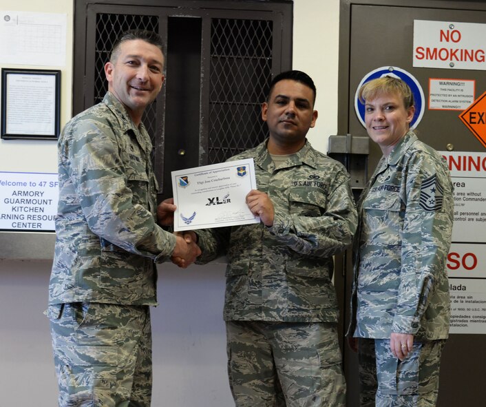 Tech. Sgt Jose Cruzbarbosa, center, 47th Security Forces Squadron anti-terrorism NCO, poses with Col. Brian Hastings, 47th Flying Training Wing commander, and Chief Master Sgt. Teresa Clapper, 47th FTW command chief, after accepting the XLer of the week award, here, April 29, 2015. The XLer is a weekly award chosen by wing leadership and was presented to Cruzbarbosa, who was one of the persons of contact for the Air Force Assistance Fund campaign that raised $33,000 for Laughlin Air Force Base; beating the goal by $5,000. (U.S. Air Force photo by Airman Brandon May)
