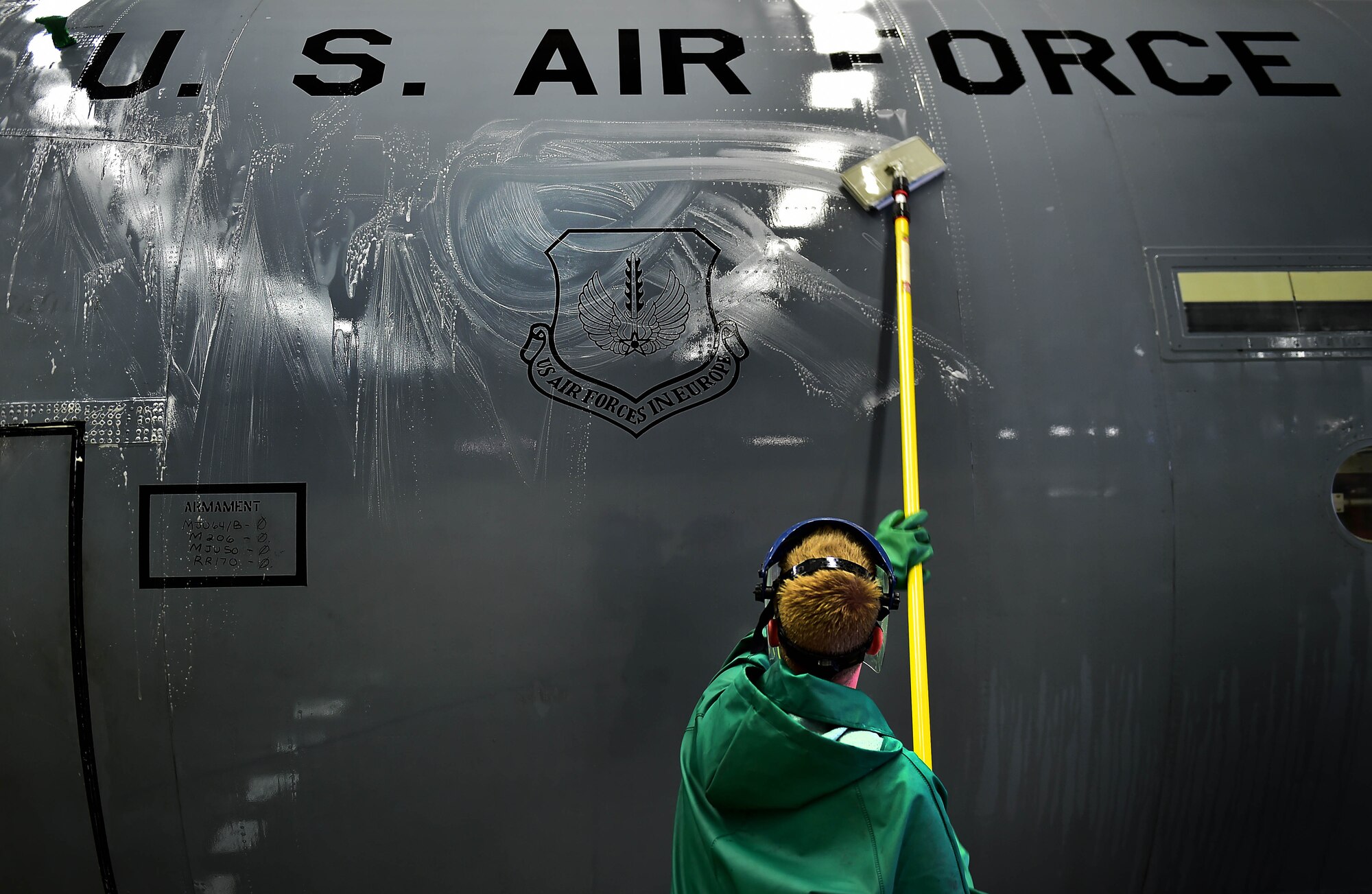 An Airman from the 86th Aircraft Maintenance Squadron washes the underside of a C-130J Super Hercules April 20, 2015, at Ramstein Air Base, Germany. Aircraft washing is a vital part of the flying mission, and if not washed regularly, aircraft begin to corrode and cause damage yielding it unsafe to operate. Safety procedures require all members participating in the washing to wear full-body protective gear. (U.S. Air Force photo/Staff Sgt. Sara Keller)