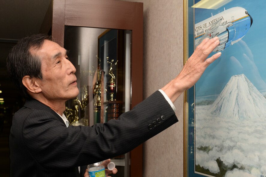 Pointing out details of the aircraft in his painting, artist Ikuo Ohsawa brings up memories of what inspired his work over 45 years ago, April 30, 2015 at Yokota Air Base, Japan. Ohsawa said that Mount Fuji appears in many of his paintings because it is the origin of his heart. (U.S. Air Force photo by Airman 1st Class Elizabeth Baker/Released)