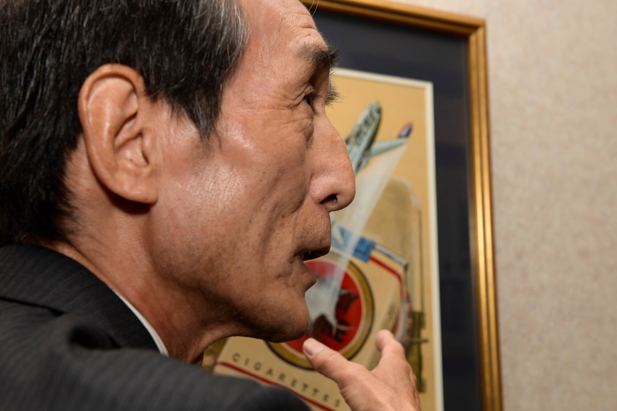Artist Ikuo Ohsawa explains the meaning behind his paintings during a tour of his artwork in the halls of the 5th Air Force Headquarters, April 30, 2015 at Yokota Air Base, Japan. Ohsawa said that he created some of the pieces for work, some on request from United States Forces Japan and some for himself. (U.S. Air Force photo by Airman 1st Class Elizabeth Baker/Released)
