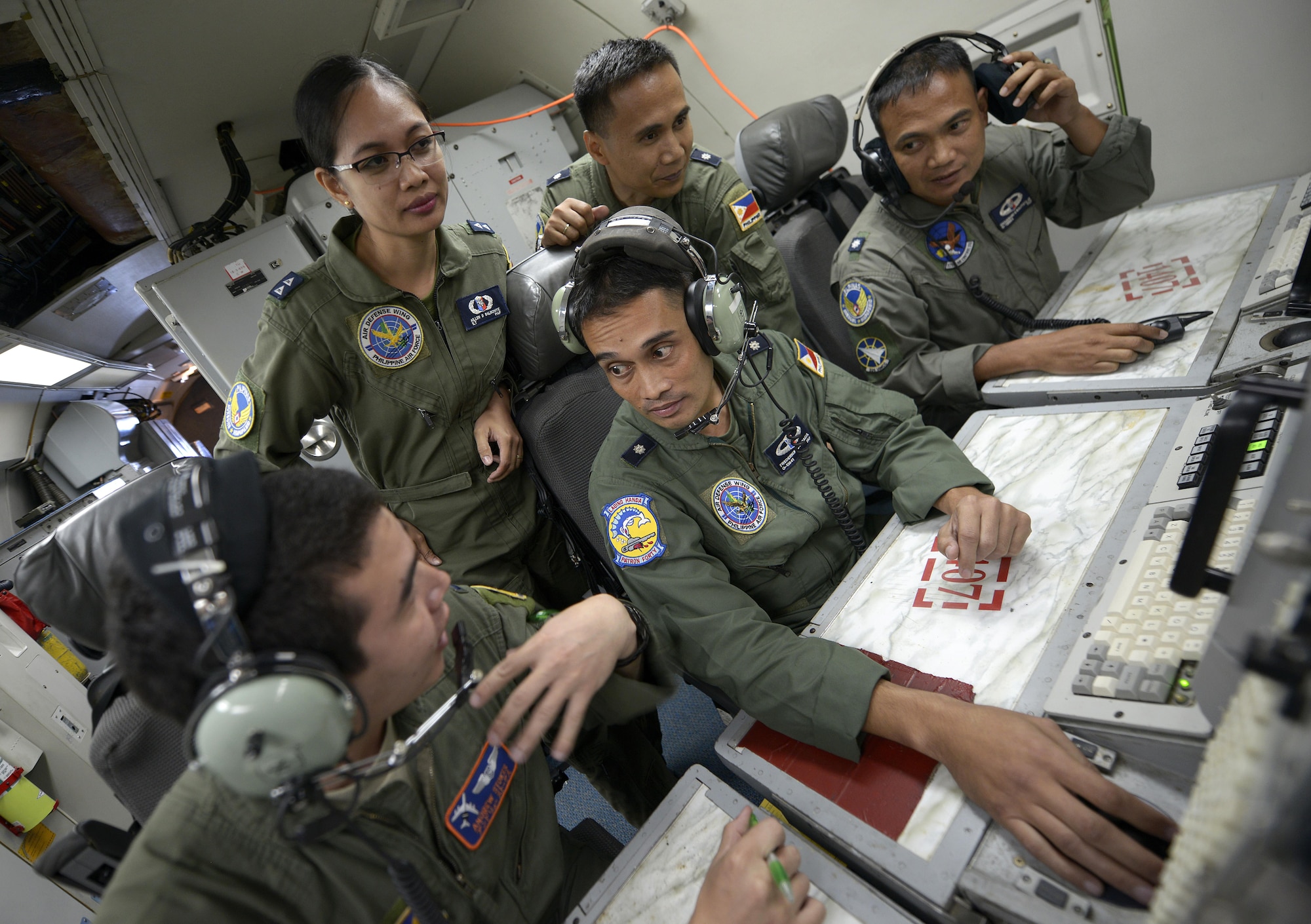 1st Lt. Andrew Stokes (left), a 961st Airborne Air Control Squadron (AACS) air weapons officer, speaks with Philippine Air Force Maj. Frederick Facia, the 581st Aircraft Control and Training Squadron commander, and other PAF air battle managers while onboard a 961st AACS E-3 Sentry AWACS during exercise Balikatan 2015 over the Philippines April 23, 2015. This exercise marks the first time in history that PAF air battle managers have controlled other aircraft while on board the AWACS. Since the exercise began, April 20, 2015, the 961st AACS has integrated 20 PAF weapons controllers during their missions in order to provide them with firsthand experience using the aircraft’s systems. The 961st AACS is stationed at Kadena Air Base, Japan. (U.S. Air Force photo/Staff Sgt. Maeson L. Elleman)