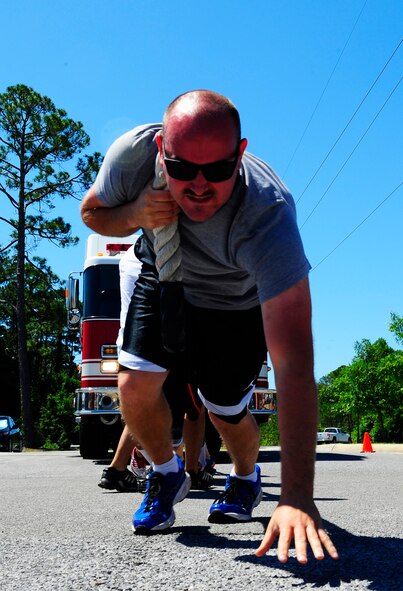 Senior Airman Paul Kon, 1st Special Operations Component Maintenance Squadron aerospace propulsion journeyman, leads his team in pulling a fire truck for fitness day at Hurlburt Field, Fla., May 6, 2015. Air Force Fitness Month promotes physical wellness and teaches Airmen how being "fit" plays a vital role in the quality of military life. (U.S. Air Force photo/Airman 1st Class Andrea Posey)