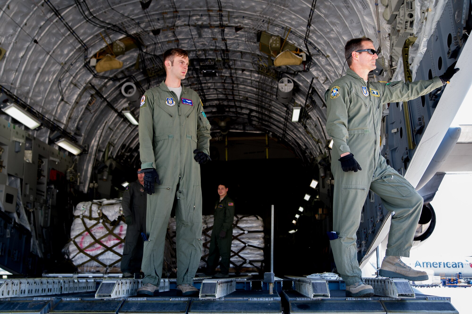 Master Sgt. Ken Hundemer, 317th Airlift Squadron loadmaster, and Tech Sgt. Cody Harris, 701st Airlift Squadron loadmaster, awaits the arrival of a cargo offload vehicle April 23, 2015 in Haiti during a four-day training mission to Key West Naval Air Station, Fla. The 315th Airlift Wing flew 20 sorties during the four-day deployment and airlifted more than 345,000 pounds of humanitarian cargo, which included 61 pallets of food and clothing and one school bus. Hundemer he also serves as the Denton Program director of operations in his civilian capacity. (U.S. Air Force Photo by Tech. Sgt. Shane Ellis)