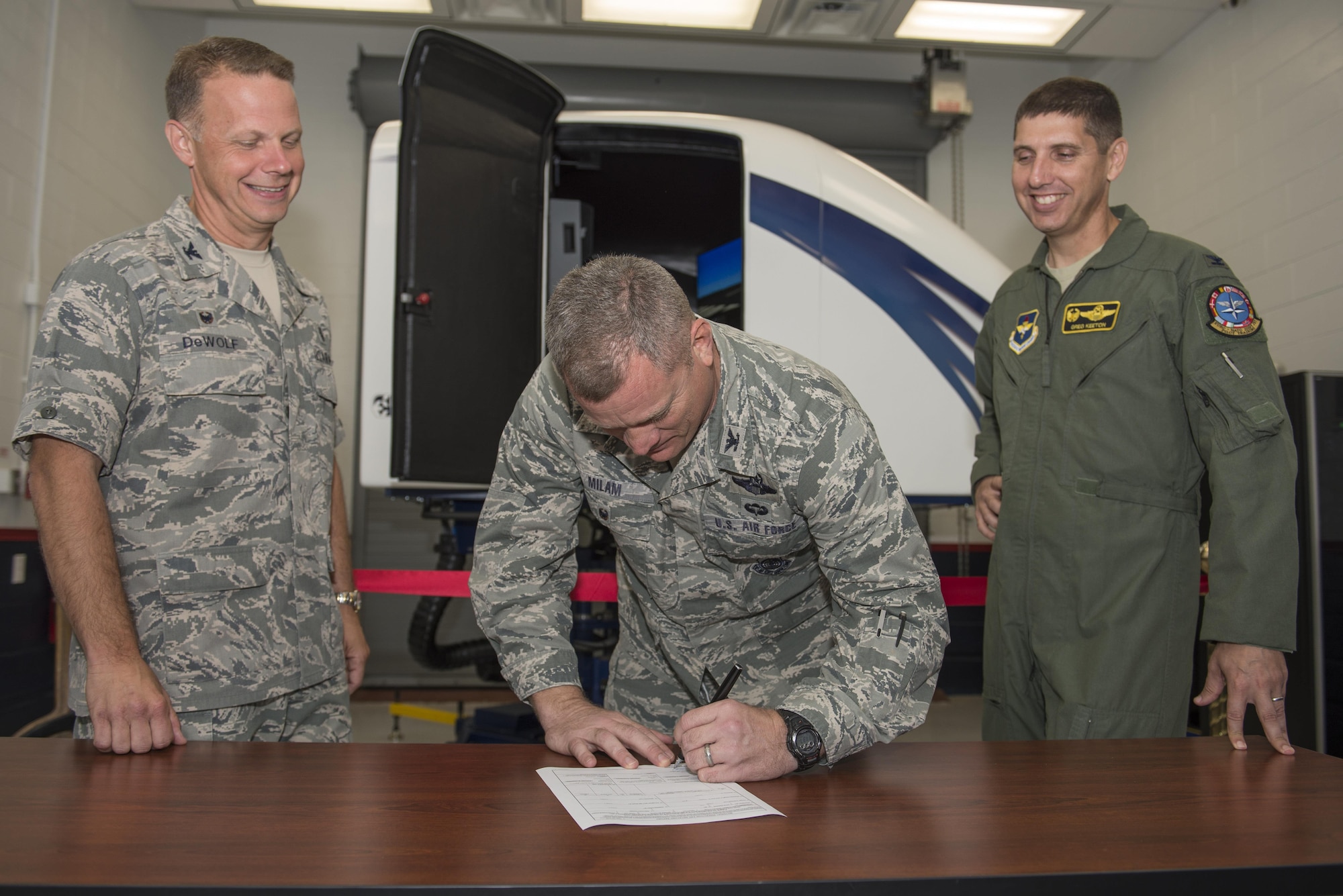 U.S. Air Force Col. Samuel Milam, Air Education and Training Command deputy director of intelligence operations and nuclear intelligence for flying training, (middle), signs the formal acceptance of AETC’s first Spatial Disorientation Trainer beside Col. Gregory DeWolf, 82nd Medical Group commander, (left), and Col. Gregory Keeton, 80th Flying Training Wing commander, at Sheppard Air Force Base May 7, 2015. The trainer is intended to teach pilots how to correctly identify different types of air sickness they may encounter during flight. (U.S. Air Force photo by Senior Airman Kyle Gese/Released)