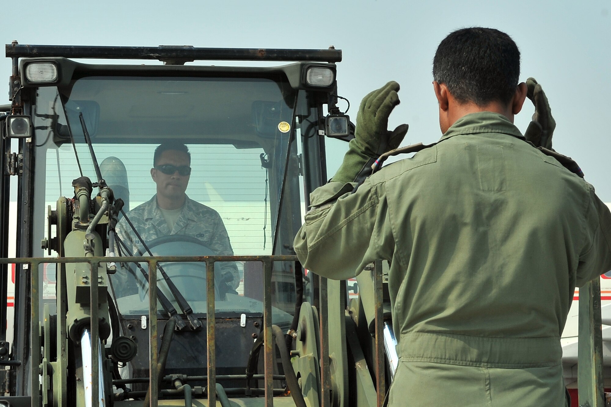 A Bangladesh air force member guides U.S. Air Force Tech. Sgt. Gabriel Hayashi, 36th Mobility Response Squadron aerospace ground equipment craftsman, as he transfers pallets with a forklift May 7, 2015, at the Tribhuvan International Airport in Kathmandu, Nepal. The Nepalese Army and Airmen worked with military members from the Bangladesh air force and Indian air force to process cargo from their aircraft arriving in Nepal to provide disaster relief following a magnitude 7.8 earthquake that struck the nation April 25. (U.S. Air Force photo by Staff Sgt. Melissa White/Released)