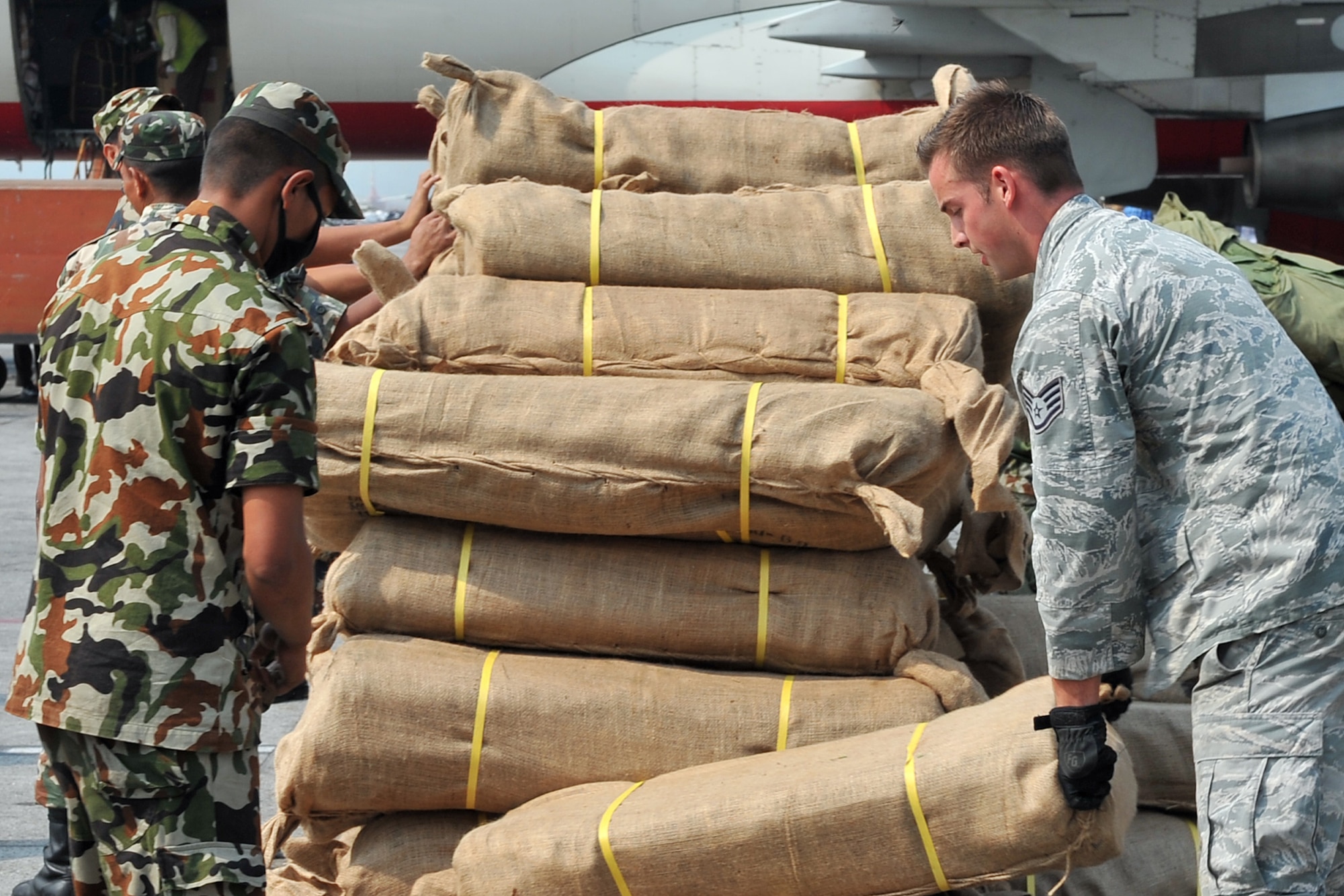 U.S. Air Force Master Sgt. Shane Reed, 36th Mobility Response Squadron operations superintendent, and a Bangladesh Air Force member wrap up cargo straps after unloading relief supplies from a BAF C-130 Hercules May 7, 2015, at the Tribhuvan International Airport in Kathmandu, Nepal. The Nepalese Army and Airmen worked with military members from the Bangladesh Air Force and Indian Air Force to process cargo from their aircraft arriving in Nepal to provide disaster relief following a magnitude 7.8 earthquake that struck the nation April 25.  (U.S. Air Force photo by Staff Sgt. Melissa White/Released)