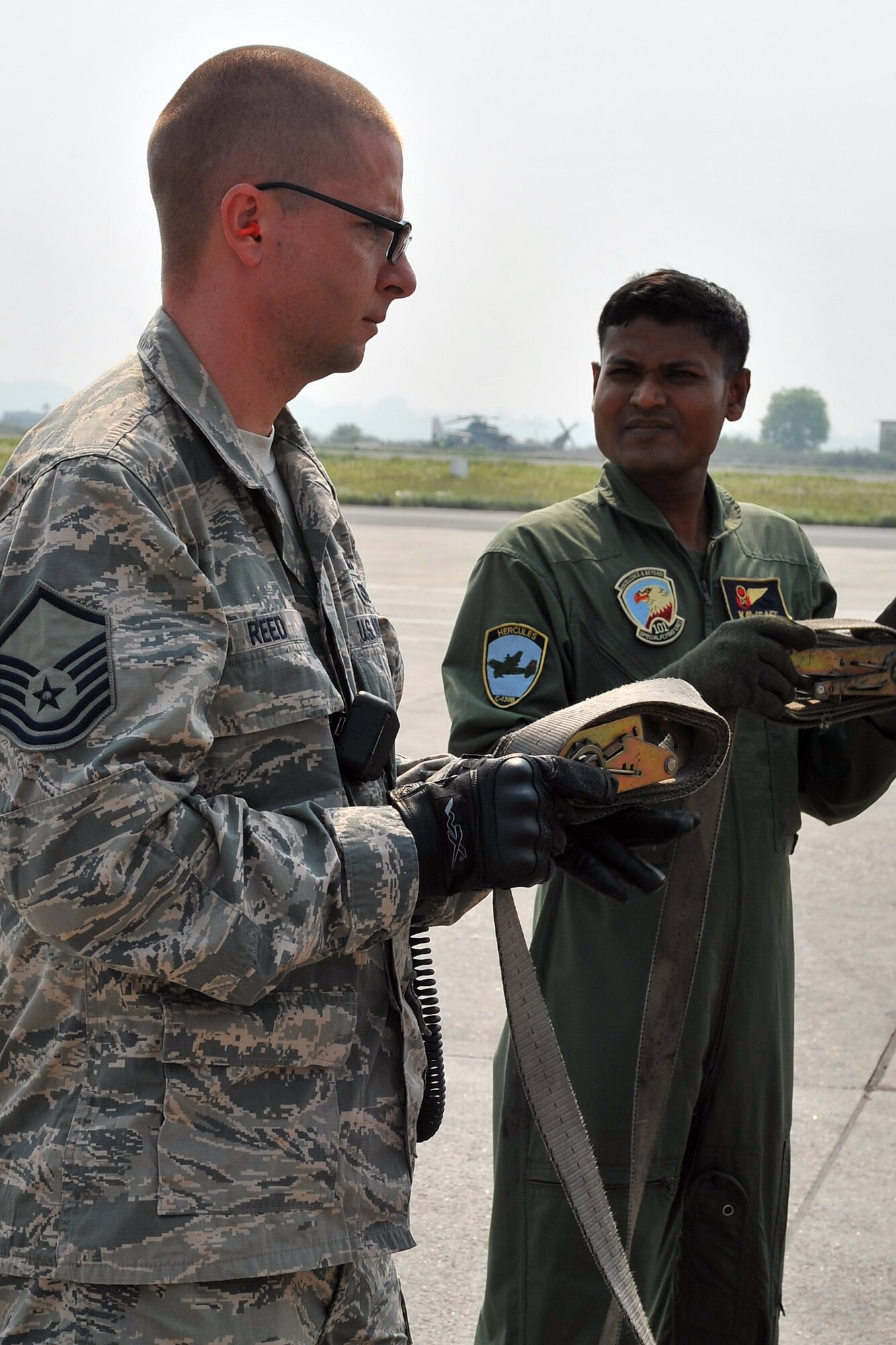 U.S. Air Force Master Sgt. Shane Reed, 36th Mobility Response Squadron operations superintendent, and a Bangladesh Air Force member wrap up cargo straps after unloading relief supplies from a BAF C-130 Hercules May 7, 2015, at the Tribhuvan International Airport in Kathmandu, Nepal. The Nepalese Army and Airmen worked with military members from the Bangladesh Air Force and Indian Air Force to process cargo from their aircraft arriving in Nepal to provide disaster relief following a magnitude 7.8 earthquake that struck the nation April 25.  (U.S. Air Force photo by Staff Sgt. Melissa White/Released)