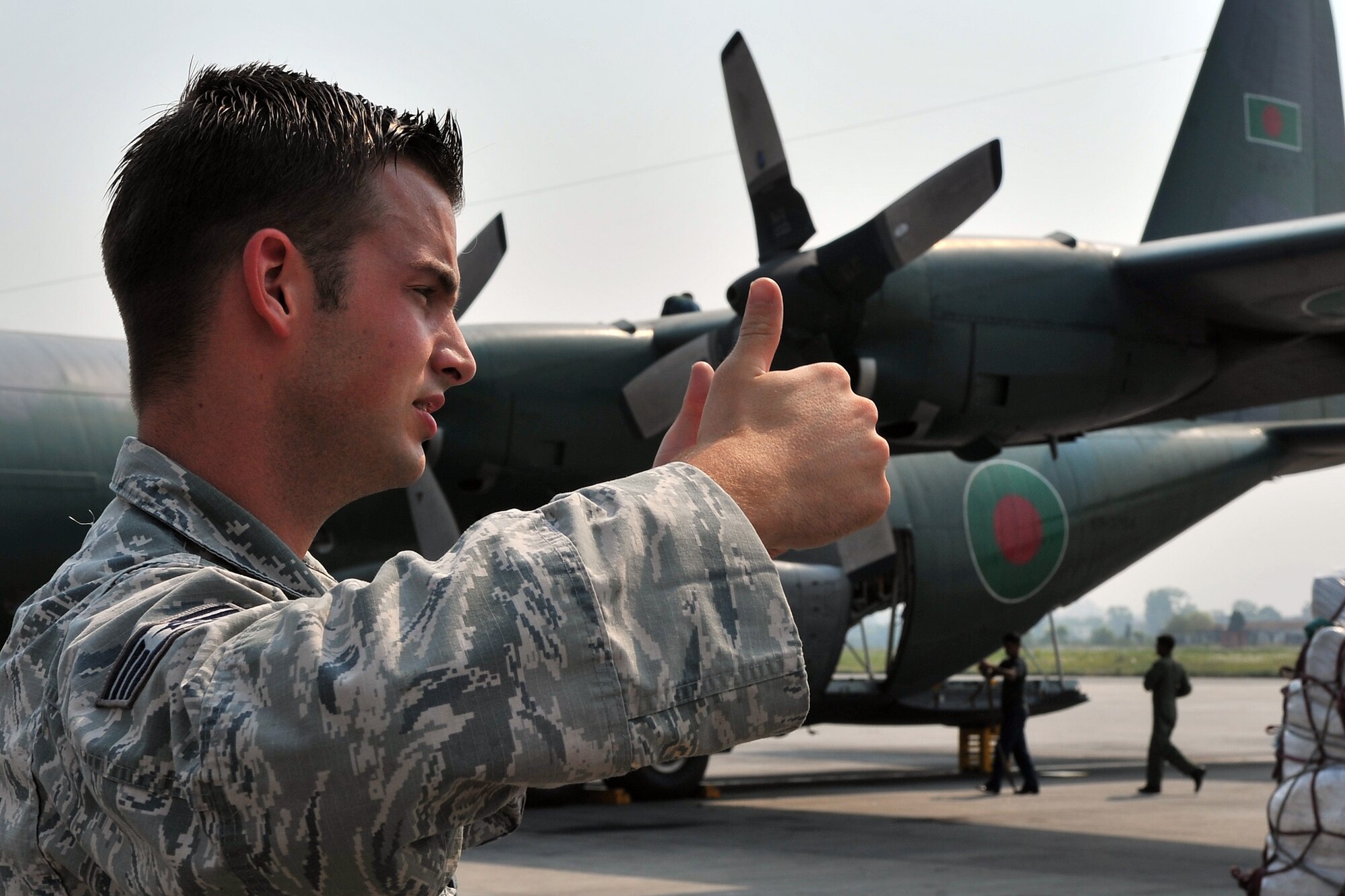 U.S. Air Force Staff Sgt. Josh Foley, 36th Mobility Response Squadron aerial port supervisor, guides an Airman offloading relief supplies from a Bangladesh Air Force C-130 Hercules May 7, 2015, at the Tribhuvan International Airport in Kathmandu, Nepal. The Nepalese Army and Airmen worked with military members from the Bangladesh Air Force and Indian Air Force to process cargo from their aircraft arriving in Nepal to provide disaster relief following a magnitude 7.8 earthquake that struck the nation April 25. (U.S. Air Force photo by Staff Sgt. Melissa White/Released)