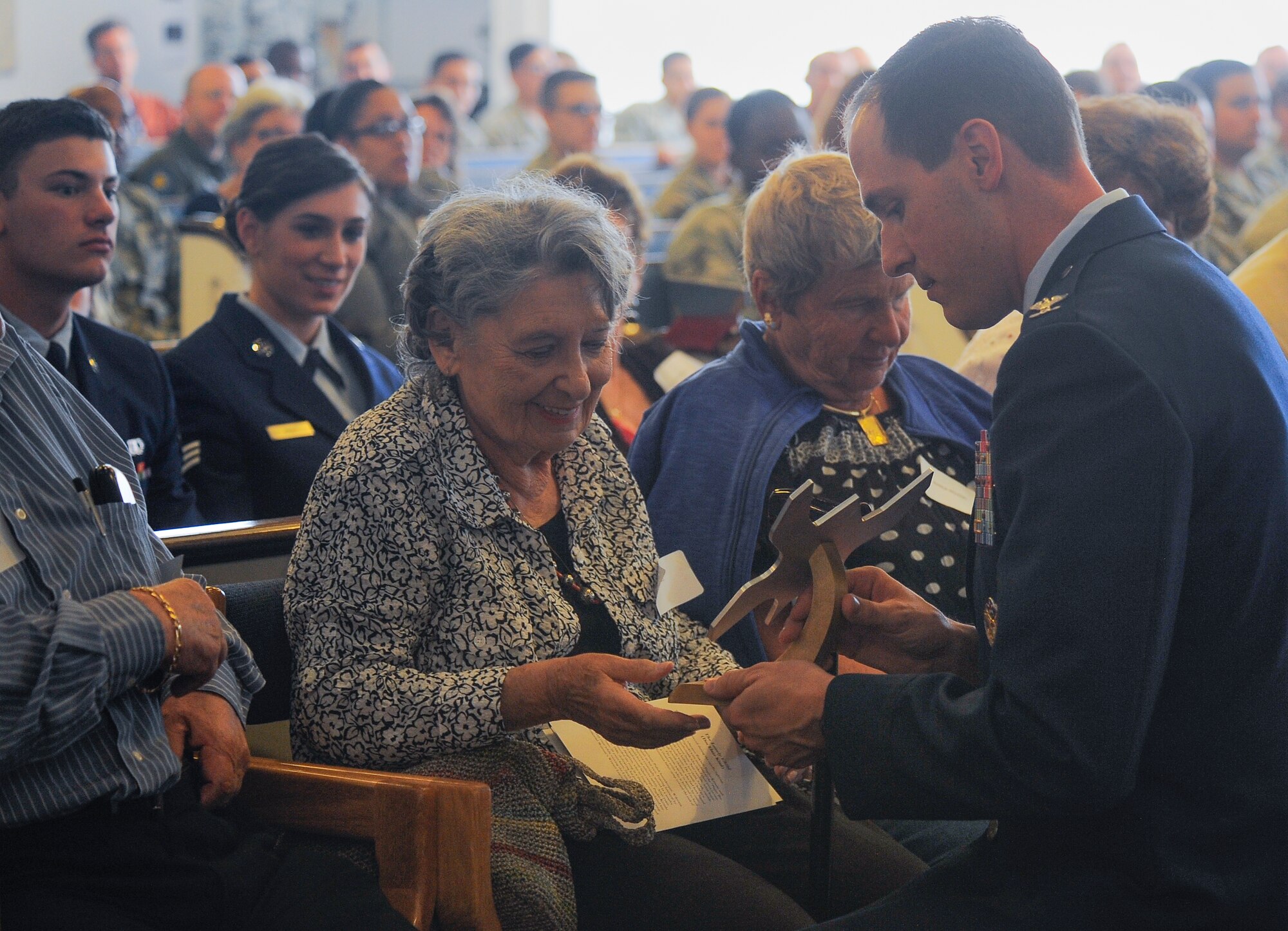 Lilly Brull, Holocaust survivor, is presented with a memento of appreciation from Col. James Meger, 355th Fighter Wing commander, during the Holocaust Day of Remembrance at Davis-Monthan Air Force Base, Ariz., May 7, 2015. The memento was created from  aircraft aluminum and shaped like a butterfly to represent freedom and hope. 