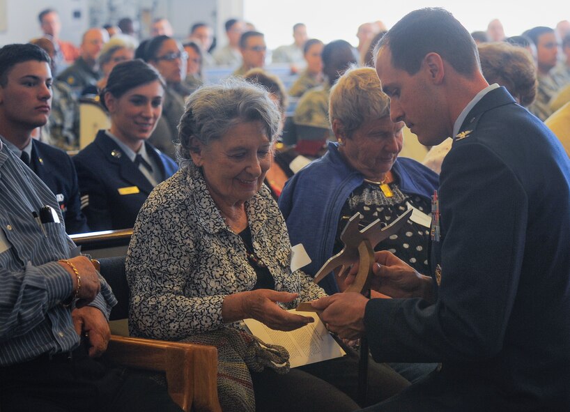 Lilly Brull, Holocaust survivor, is presented with a memento of appreciation from Col. James Meger, 355th Fighter Wing commander, during the Holocaust Day of Remembrance at Davis-Monthan Air Force Base, Ariz., May 7, 2015. The memento was created from  aircraft aluminum and shaped like a butterfly to represent freedom and hope. 