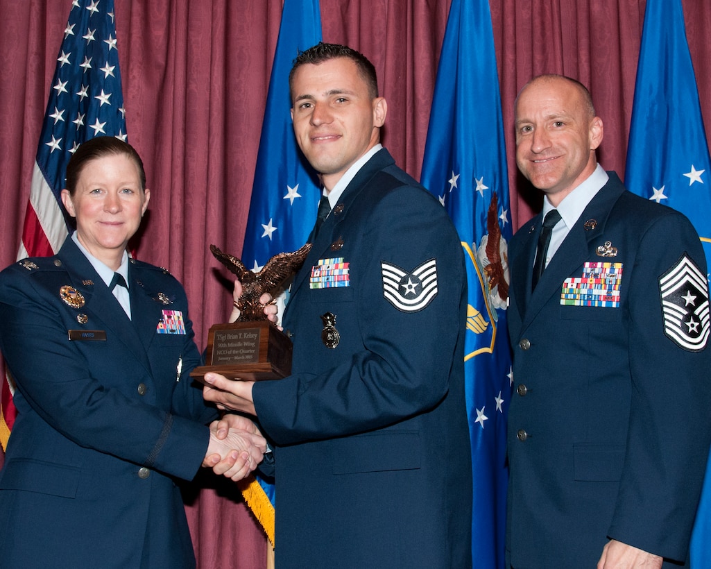 Technical Sgt. Brian Kelsey, 90th Missile Security Forces Squadron, poses with Col. Tracey Hayes, 90th Missile Wing commander, and Chief Master Sgt. Samuel Couch, 90th MW command chief, at the 90th MW First Quarter Awards Breakfast, May 8, 2015, in the Trail’s End Club on F.E. Warren Air Force Base, Wyo. Kelsey won NCO of the Quarter for the wing. (U.S. Air Force photo by Senior Airman Jason Wiese)