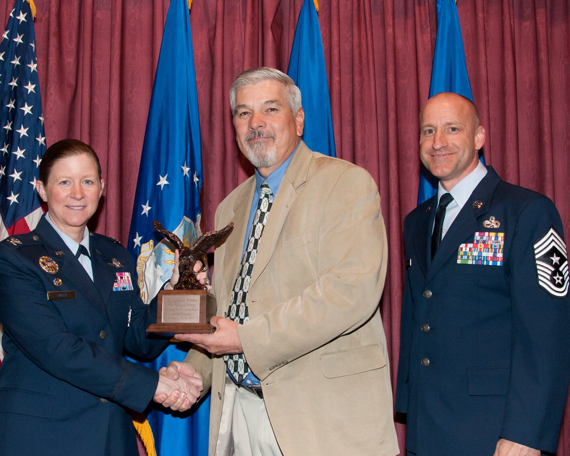 Anthony Fontes, 90th Medical Operations Squadron, poses with Col. Tracey Hayes, 90th Missile Wing commander, and Chief Master Sgt. Samuel Couch, 90th MW command chief, at the 90th MW First Quarter Awards Breakfast, May 8, 2015, in the Trail’s End Club on F.E. Warren Air Force Base, Wyo. Fontes won Civilian Category II Non-Supervisory of the Quarter for the wing. (U.S. Air Force photo by Senior Airman Jason Wiese)